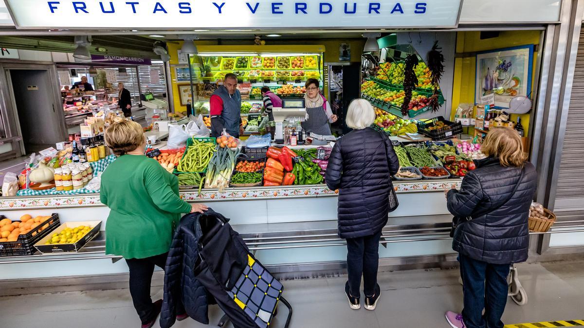 Varias mujeres esperan su turno para comprar en un puesto de frutas y verduras en el mercado de La Vila.