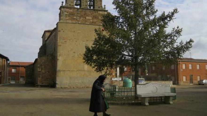 Una vecina pasa por delante de la iglesia de San Verísimo, en Alcubilla de Nogales, ayer por la mañana.