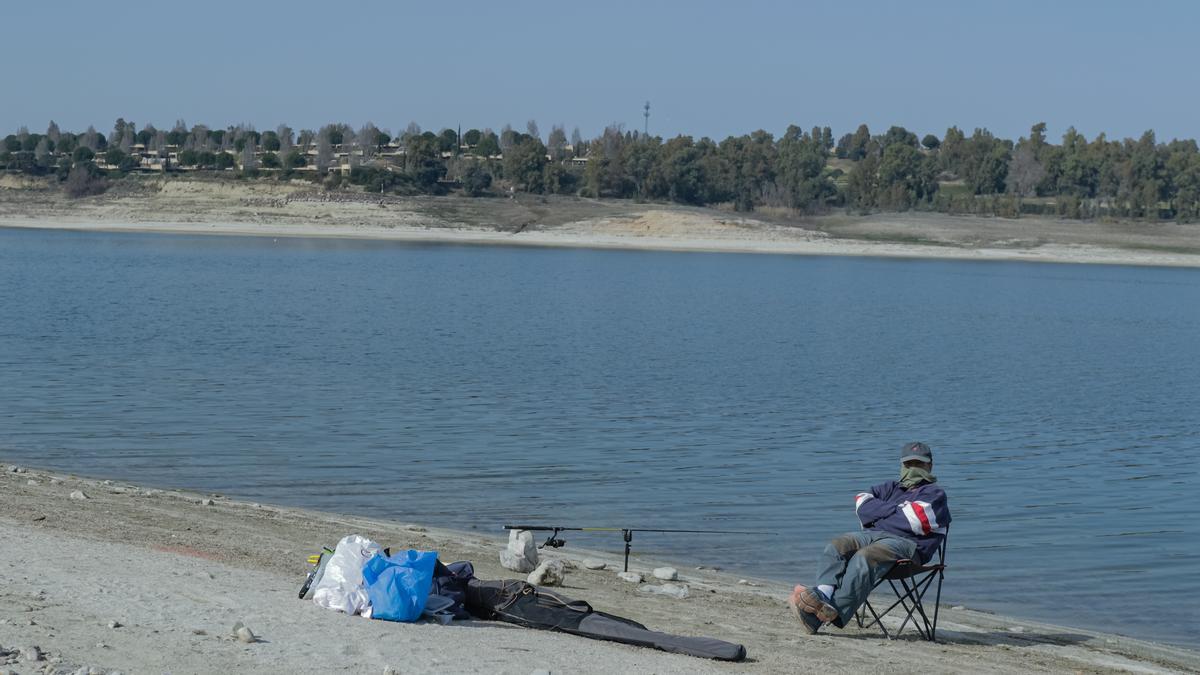 Ángel Luiz, residente en Madrid y vecino de Calzada de Oropesa, pescanso en el embalse de Valdecañas con el complejo turístico de fondo.