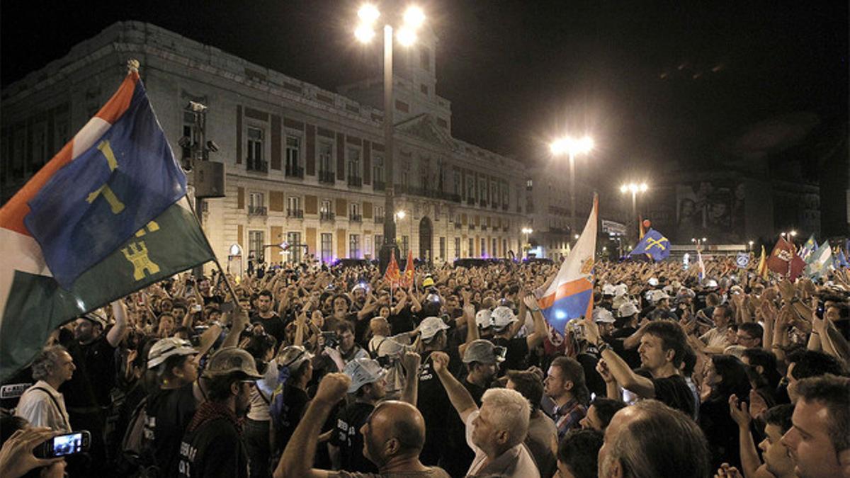 Miles de personas acompañan a los mineros de la 'marcha negra', la mayoría vestidos de negro y con las luces de sus cascos encendidas, a su llegada a la Puerta del Sol, en Madrid.