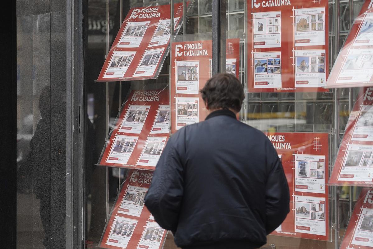 Un home davant l’aparador d’una immobiliària a Girona.