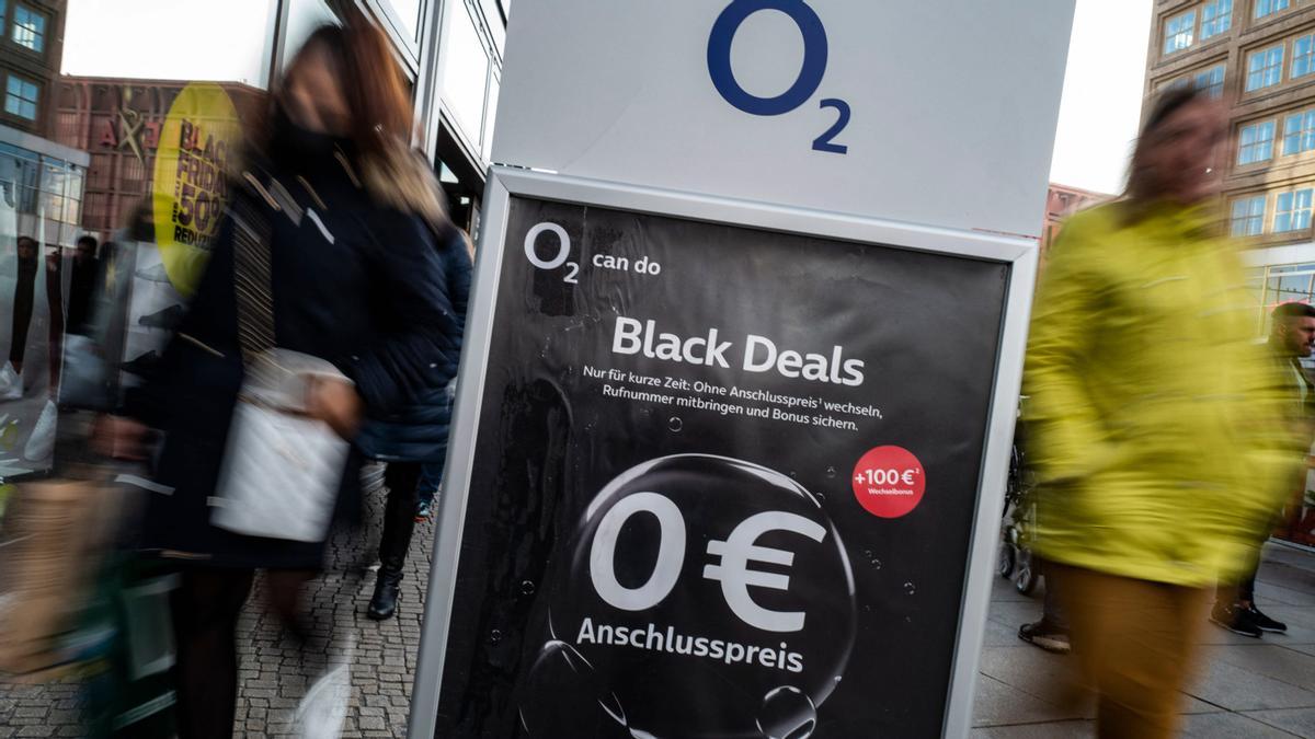 La gente pasa junto a un letrero que ofrece las promociones del llamado  Viernes Negro  en la Alexanderplatz de Berlín el 26 de noviembre de 2021