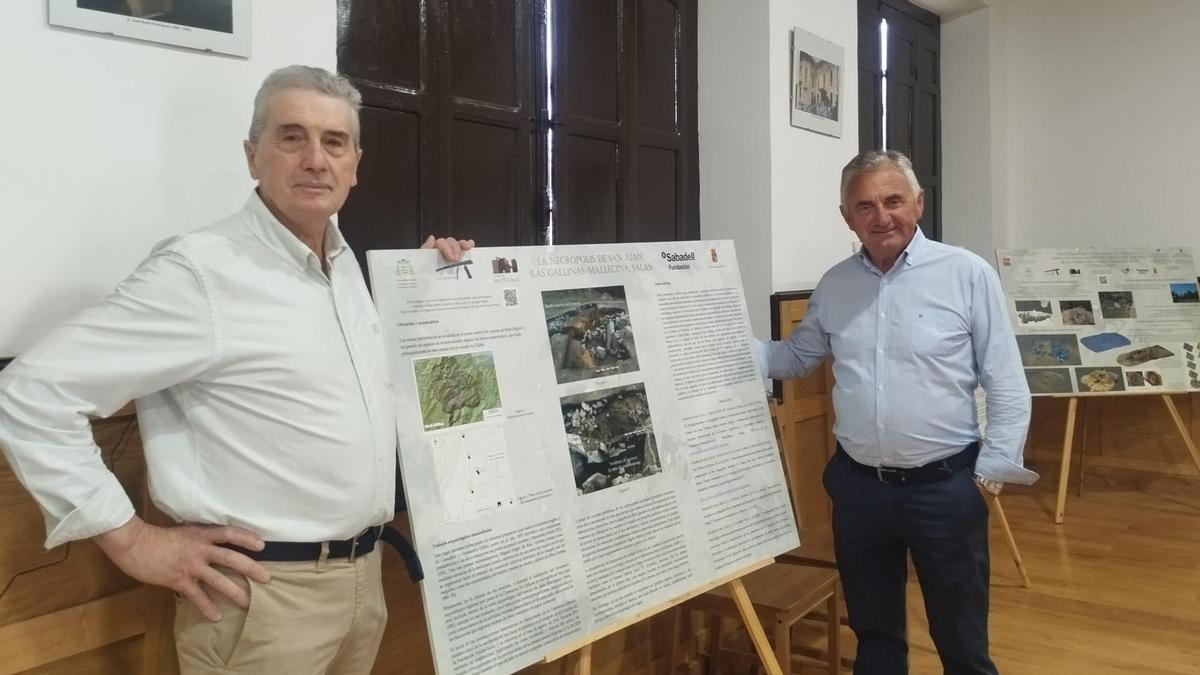 Por la izquierda, el alcalde de la parroquia de Mallecina, en Salas, Manuel Pérez, y el presidente de la Asociación Sociocultural "San Pedro", Juan Carlos Rodríguez, con uno de los paneles de la muestra sobre el dolmen de La Cobertoria en el centro social.