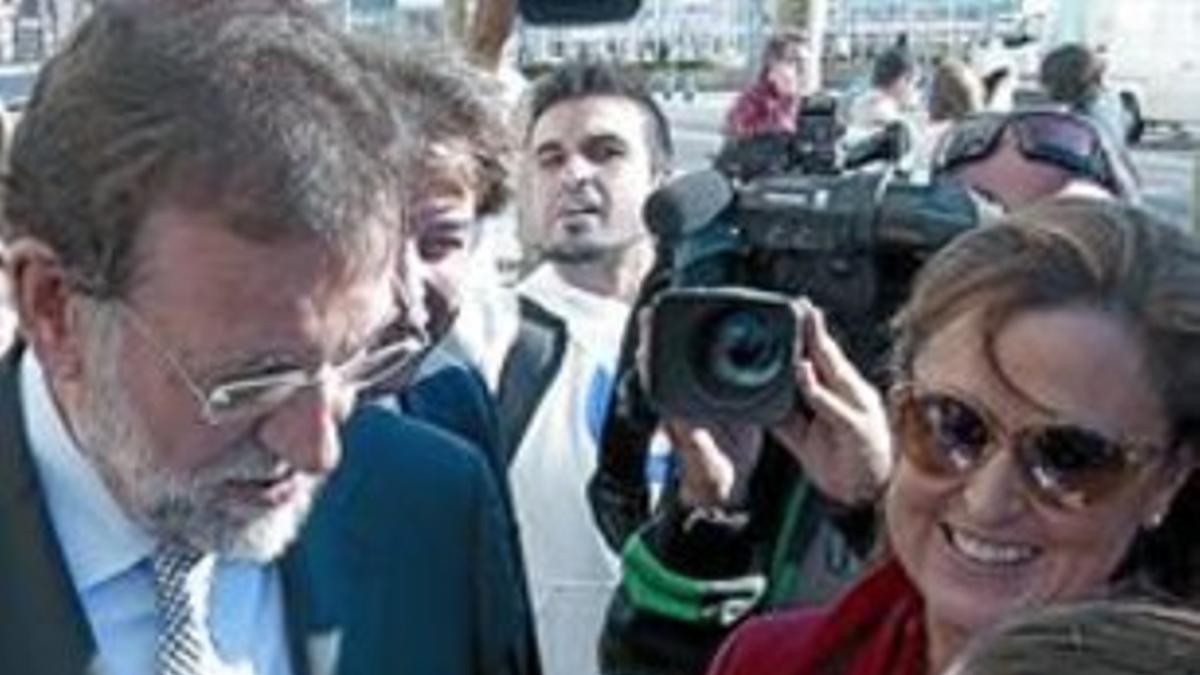 Rajoy acaricia a un niño mientras conversa con su madre durante un paseo electoral ayer en Santander.