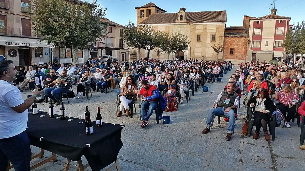 Carlos Gallego, de pie, muestra a los participantes una de las ocho botellas de vino aportadas por bodegas de la Denominación de Origen para la cata popular. | M. J. C.