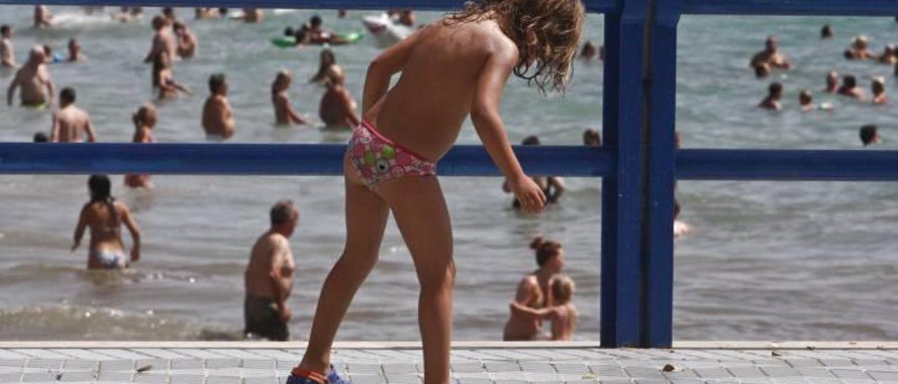 Una niña juega en el paseo del espigón de los hoteles Meliá y Portamaris en la playa alicantina del Postiguet