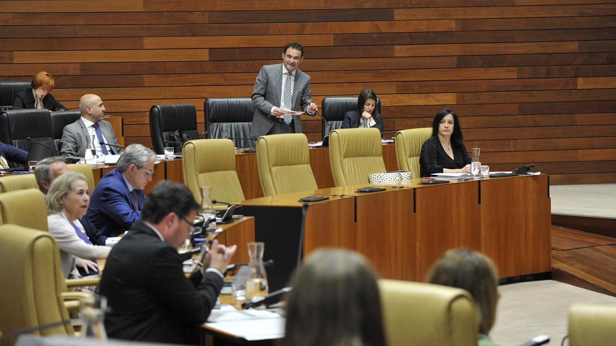El diputado socialista Jorge Amado responde al consejero de Economía, Guillermo Santamaría, sentado en su escaño.