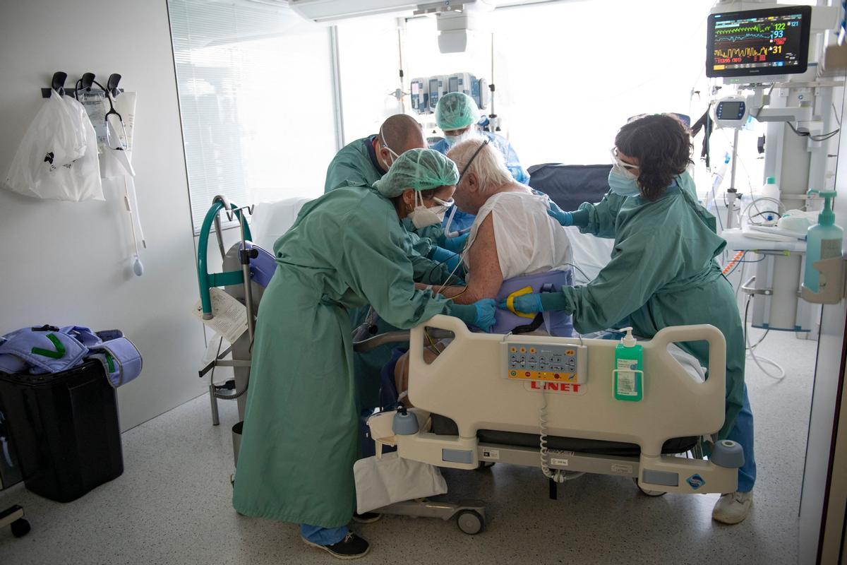 Trabajadores sanitarios ayudan a un paciente con covid ingresado en la uci del hospital Bellvitge de Barcelona, el 19 de enero de 2022.