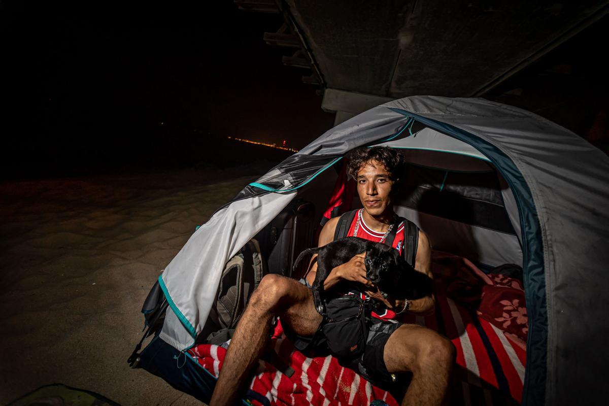 Driss, un joven de 26 años que duerme en la playa debajo de un puente, junto a su perro.