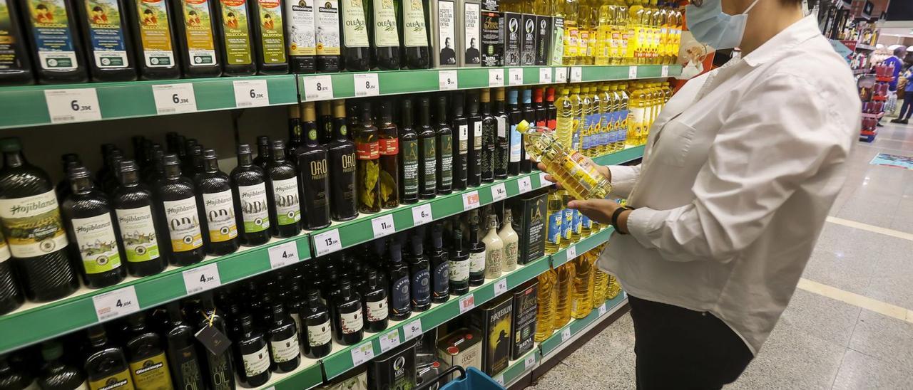 Una mujer coge una botella de aceite de girasol en un supermercado de Alicante esta semana.  | HÉCTOR FUENTES