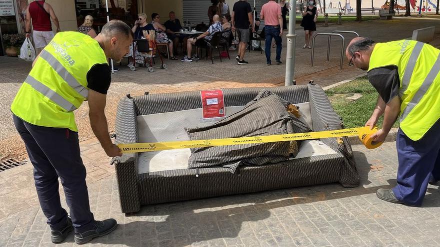 Operarios de Reciplana colocan la cinta del color correspondiente a un sofá abandonado en la vía pública.