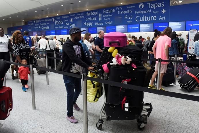 People queue with their luggage for the British ...