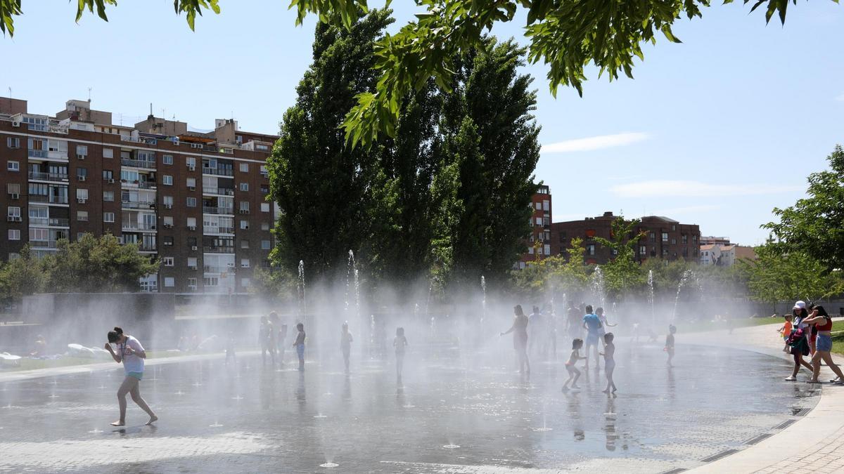 Varias personas, entre ellas niños, se refrescan en los chorros de Madrid Río.