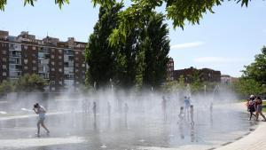 Varias personas, entre ellas niños, se refrescan en los chorros de Madrid Río.