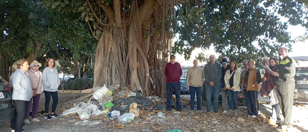 Vecinos junto a basura al pie de un ficus de la parcela, la semana pasada.