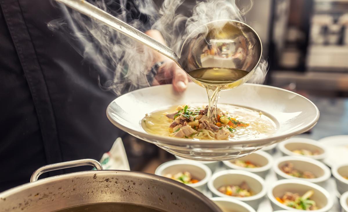 Una persona sirve un plato de sopa caliente.