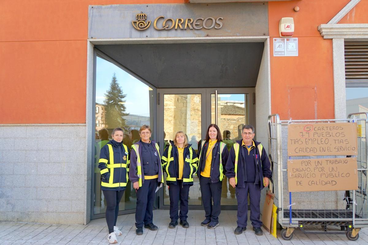 Los cinco carteros de Aliste posan en la sede junto a carteles reivindicativos.