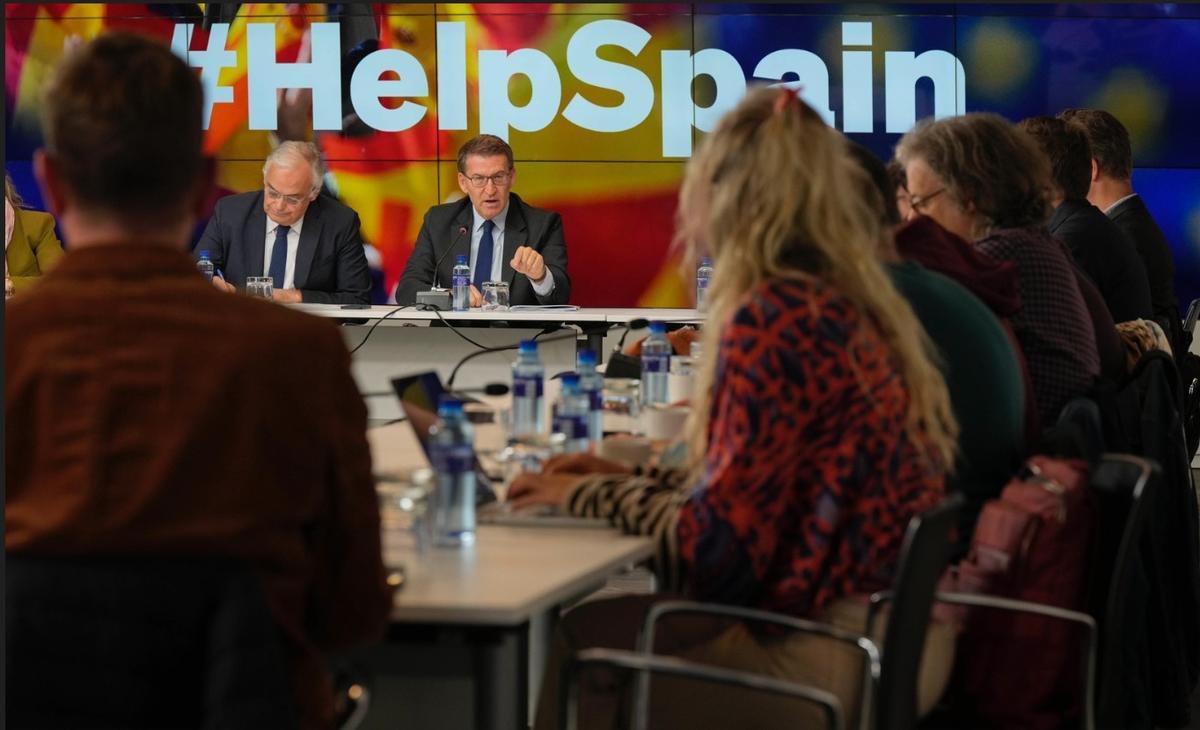 Feijóo, con los correponsales extranjeros y el lema detrás de él &quot;Ayuda a España&quot;.