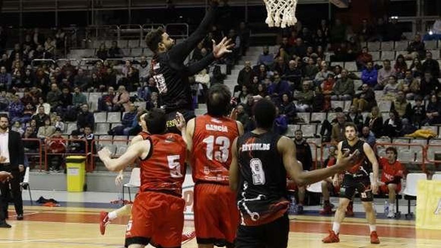 El jugador del Círculo Gijón Gregorio Adón entra a canasta ante la mirada de los navarros Carlos Calvo y Adrián García.