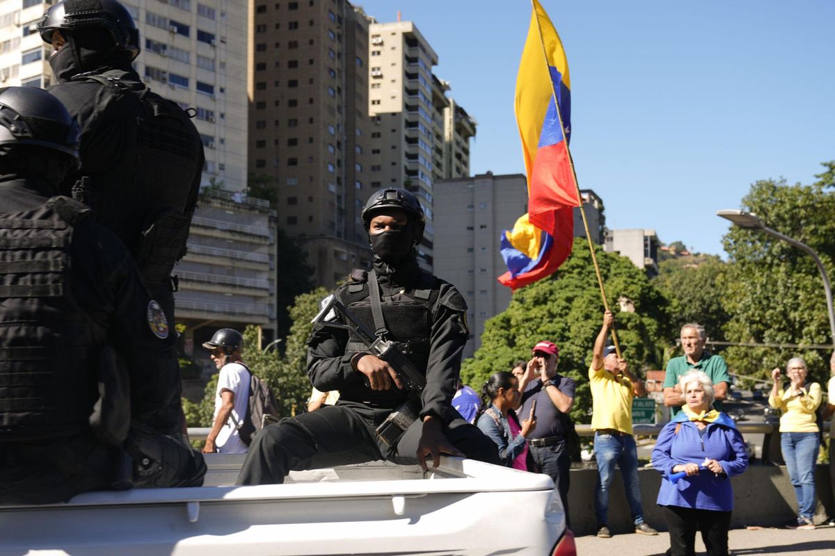 Security forces patrol past opponents of Venezuelan President Nicolas Maduro who are demonstrating the day before his inauguration for a third term in Caracas, Venezuela, Thursday, Jan. 9, 2025. (AP Photo/Ariana Cubillos). EDITORIAL USE ONLY / ONLY ITALY AND SPAIN