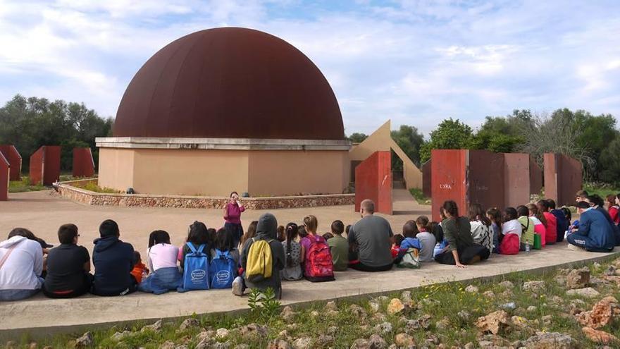 Un grupo de personas asiste a una clase en el anfiteatro del astroparque, al fondo se observa la cúpula del planetario.