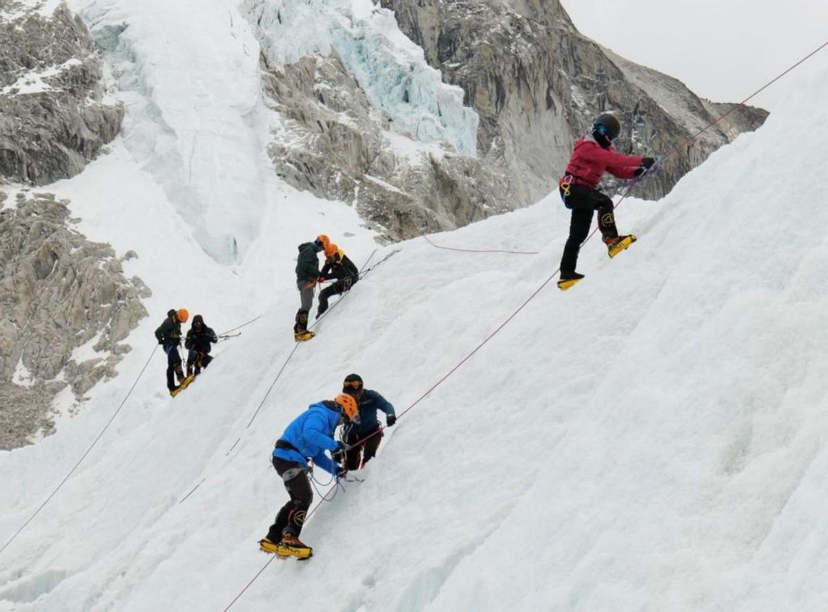 Arriba, un fotograma del documental donde unos turistas reciben clases de cómo ponerse los crampones en el campo base del Everest; sobre estas líneas, Jean-Michel Jorda, en el Himalaya. Al lado, cartel del documental. | «Everest Invaders»