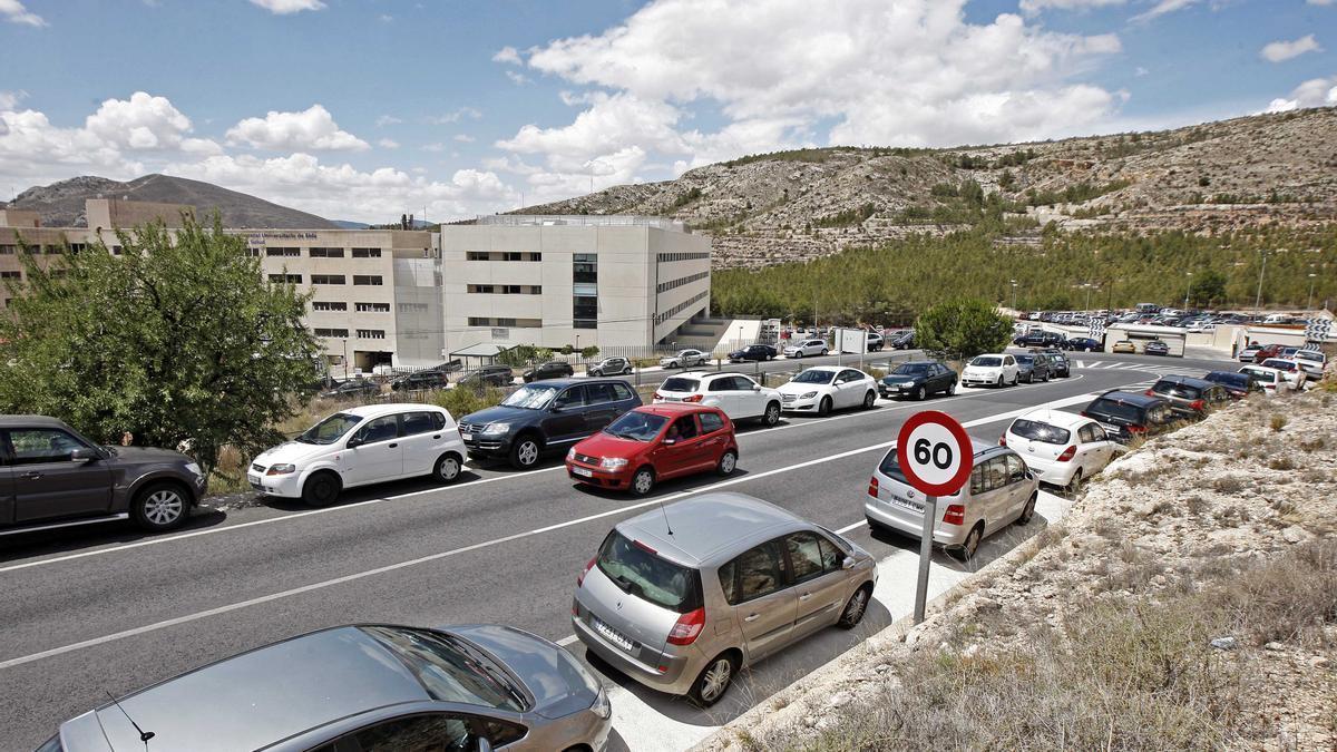 Los vehículos estacionados en el arcén de la carretera comarcal de La Torreta con el Hospital de Elda al fondo.