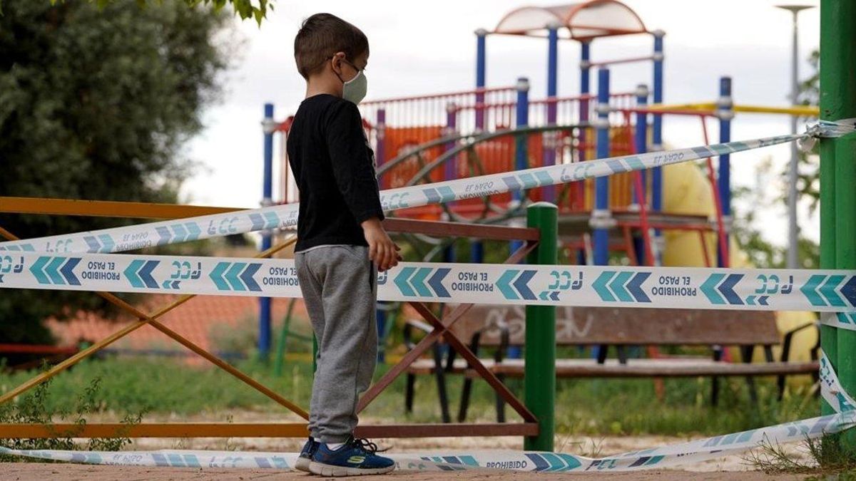 Un niño con mascarilla, frente a un parque infantil que continúa cerrado a pesar de la desescalada.