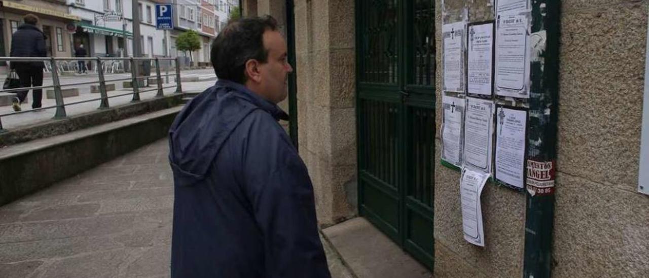 Un vecino contempla esquelas en el panel de la Praza de Abastos de Lalín. // Bernabé/Gutier