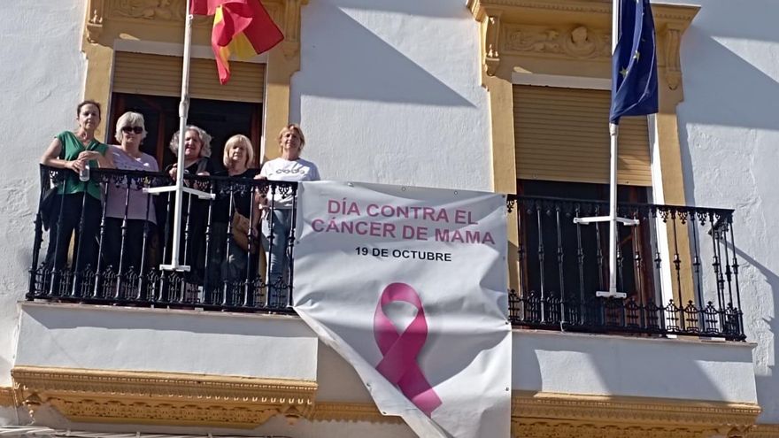 Aoex Monesterio despliega un gran lazo rosa en la fachada principal del ayuntamiento