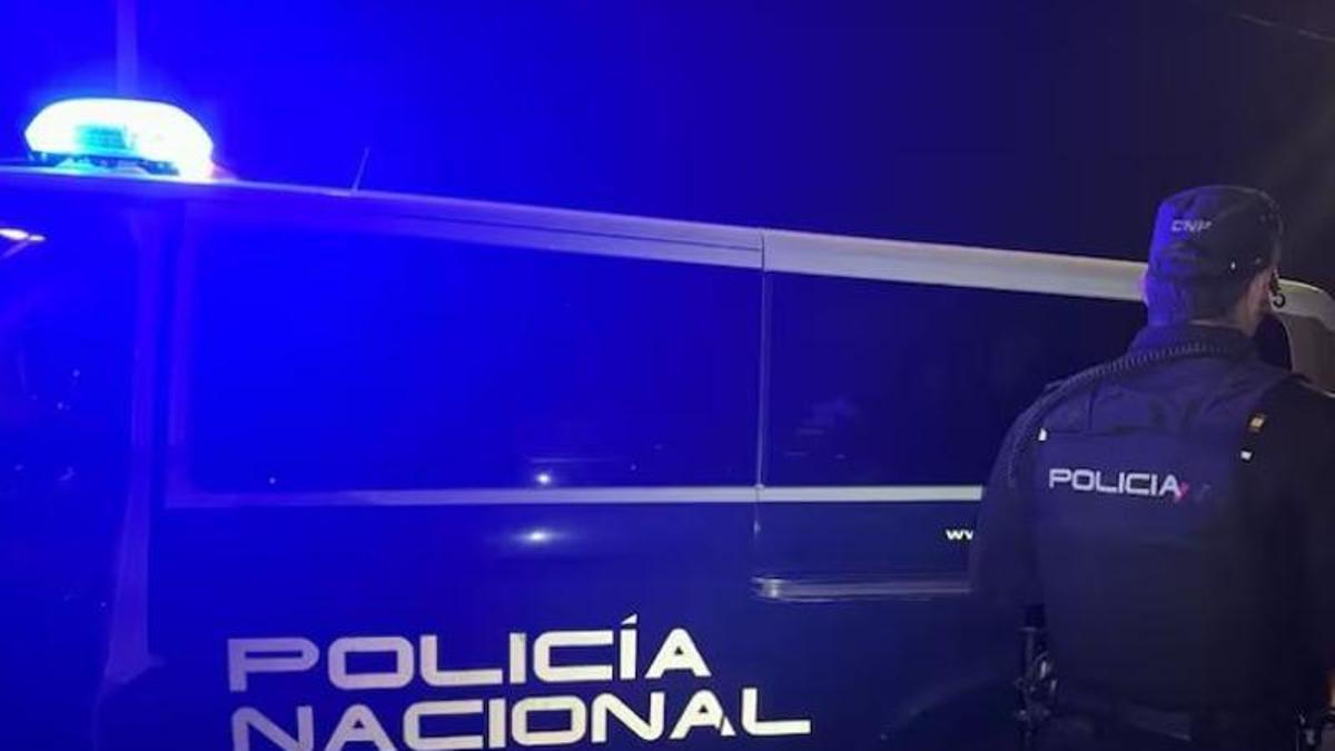 Archivo - Un agente de la Policía Nacional junto al coche policial