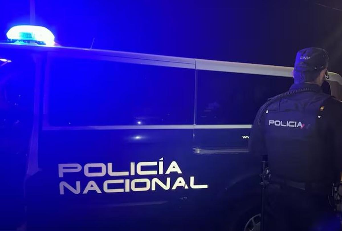 Archivo - Un agente de la Policía Nacional junto al coche policial