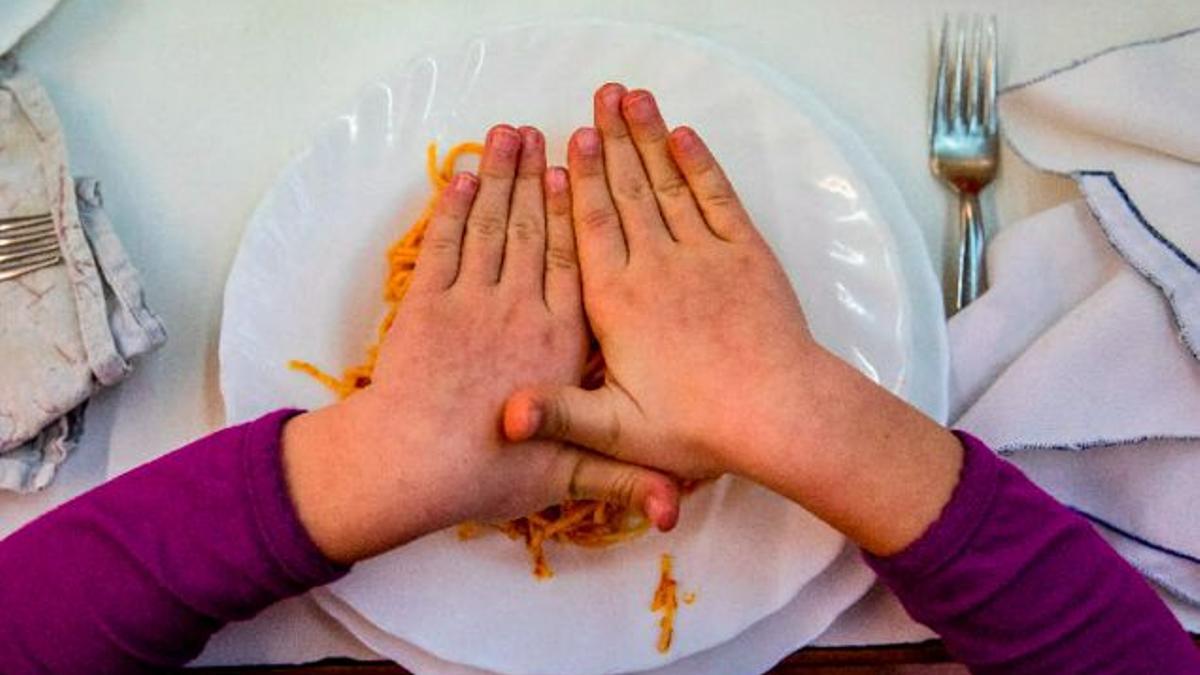 Un niño, frente a un plato de pasta en el comedor de su colegio