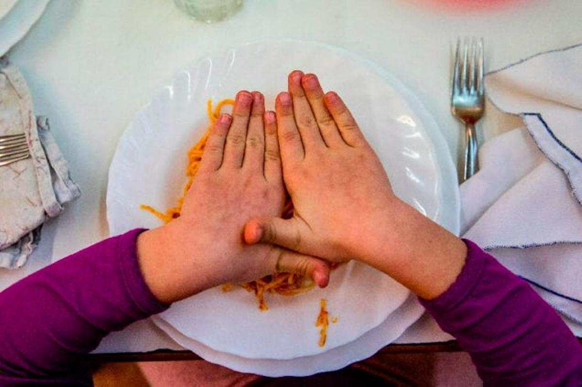 Un niño, frente a un plato de pasta en el comedor de su colegio.