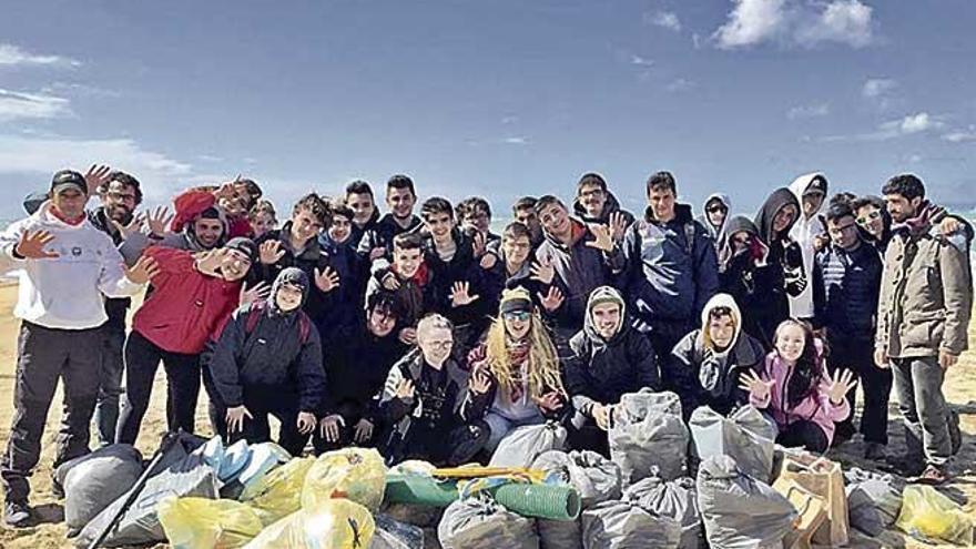 Estudiantes posan junto a los residuos recogidos en la costa.