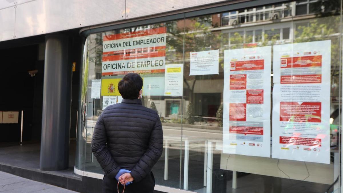 Un home passeja amb el seu gos davant un oficina de treball a Madrid