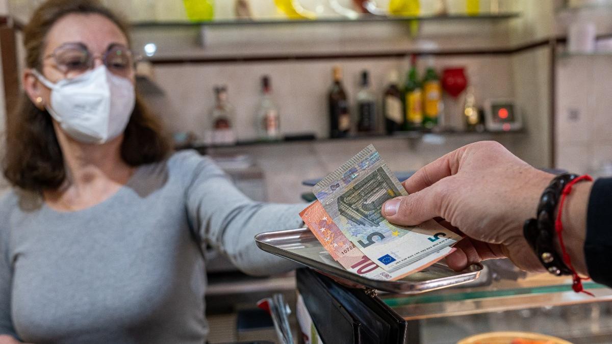 Un cliente paga la cuenta con dinero en efectivo en un bar.
