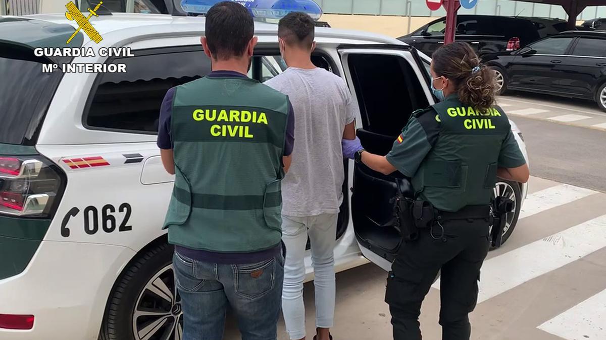 Dos guardias civiles introduciendo a uno de los detenido en el vehículo.