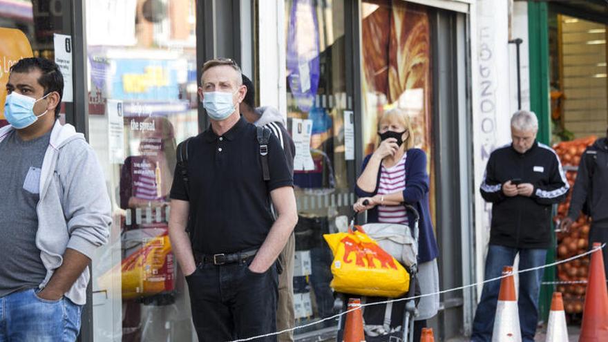 Ciudadanos de Londres hacen cola para entrar a un comercio.