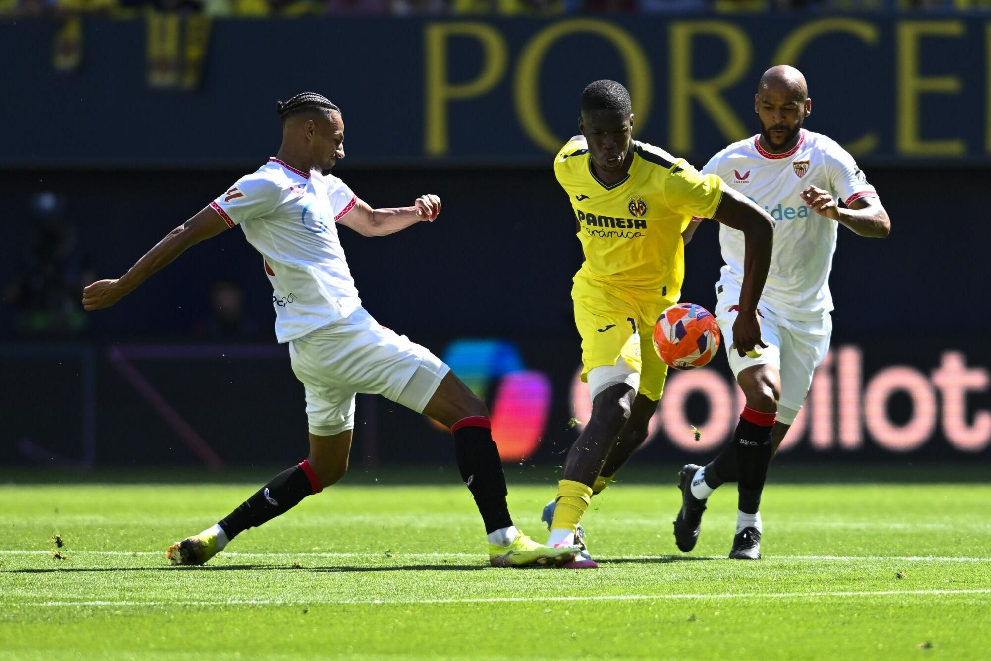 VILLARREAL (CASTELLÓN), 25/05/2025.- El delantero francés del Villarreal Thierno Barry (c) juega un balón ante la presión del Sevilla este domingo, durante el partido de la jornada 38 de LaLiga EA Sports, que Villarreal y Sevilla disputan en el Estadio de la Cerámica. EFE/ Andreu Esteban