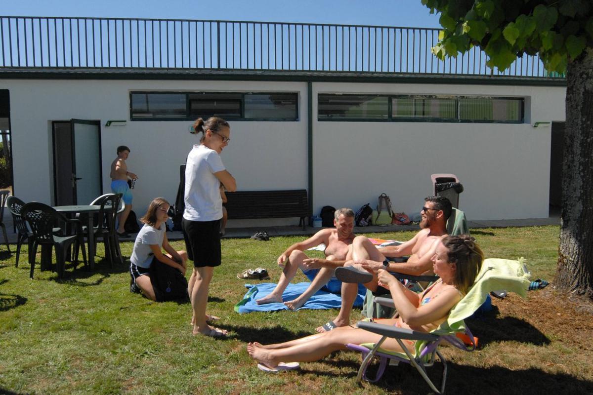 Un grupo de personas al sol en la piscina de A Bandeira. | BERNABÉ/JAVIER LALÍN