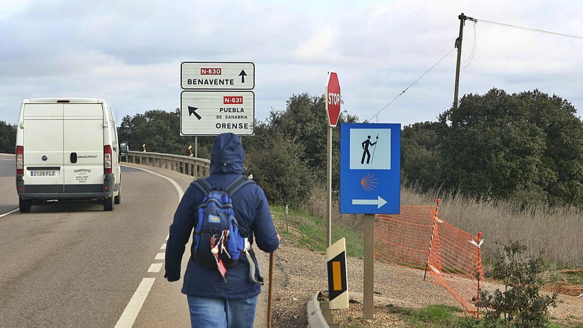 Un peregrino avanza por la carretera al encontrarse con el camino cortado. |