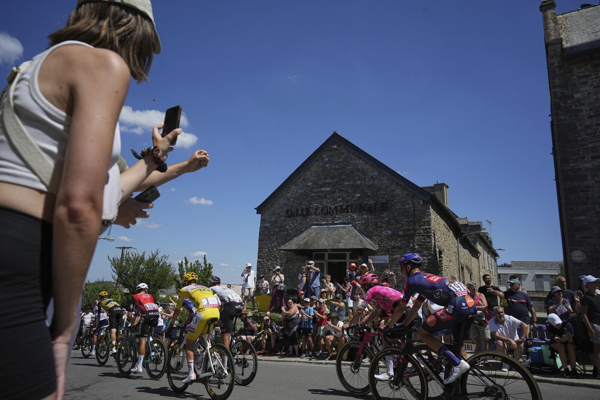 Spectators watch the pack with Slovenia's Tadej Pogacar, wearing the overall leader's yellow jersey, pass during the eighth stage of the Tour de France cycling race over 171.4 kilometers (106.5 miles) with start in Saint-Meen-le-Grand and finish in Laval Espace Mayenne, France, Saturday, July 12, 2025. (AP Photo/Thibault Camus)