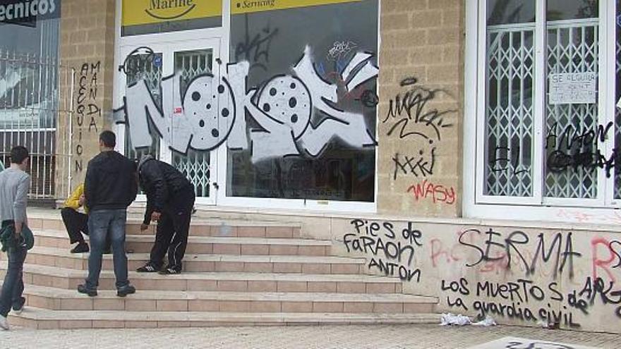 Muchas paredes del casco urbano siguen llenas de pintadas y grafitis como la que se observa en la imagen en el paseo del Maestro Velero.