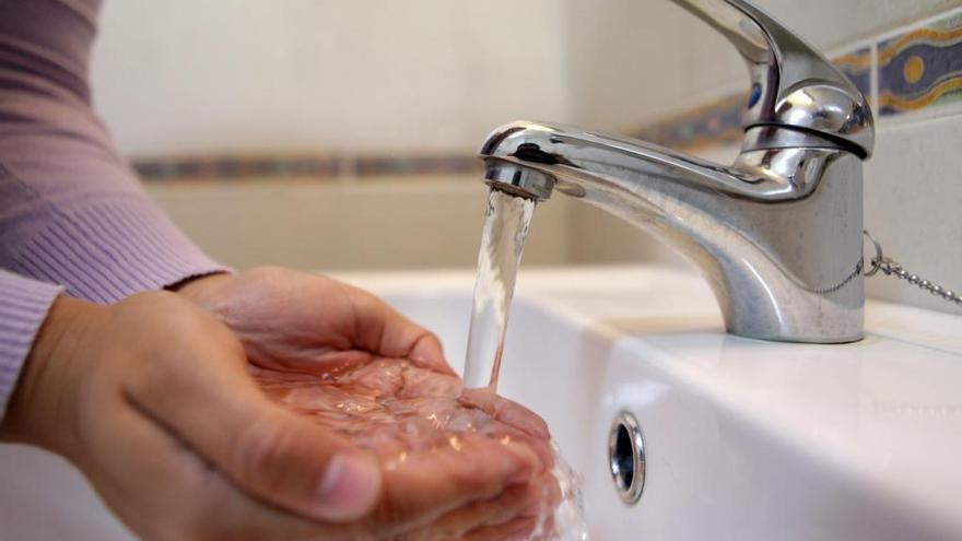 Un hombre coge agua con las manos.