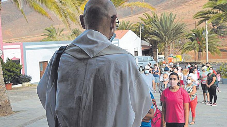 El cura José Luis Cabrera junto a la cola de feligreses.