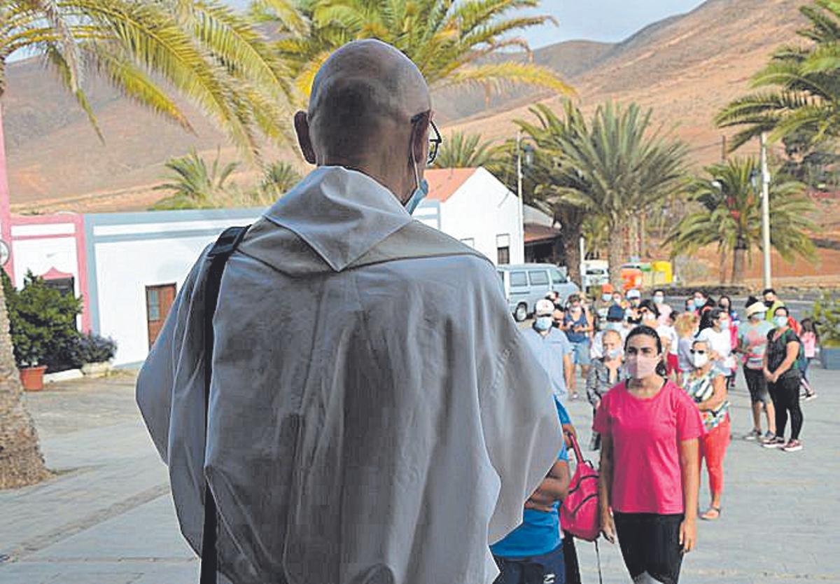 El cura José Luis Cabrera junto a la cola de feligreses.