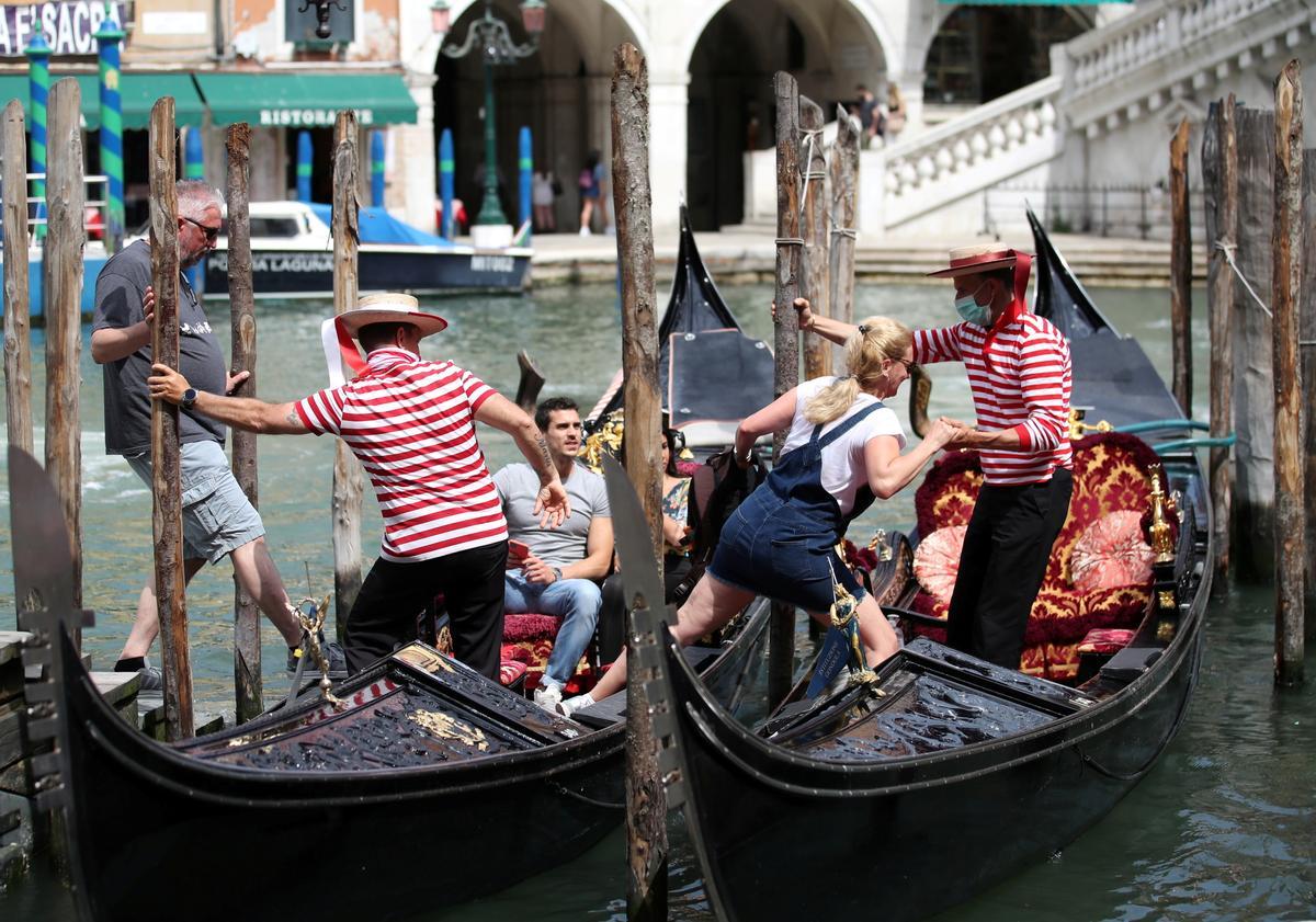 Dos turistas se suben en las góndolas en Venecia.