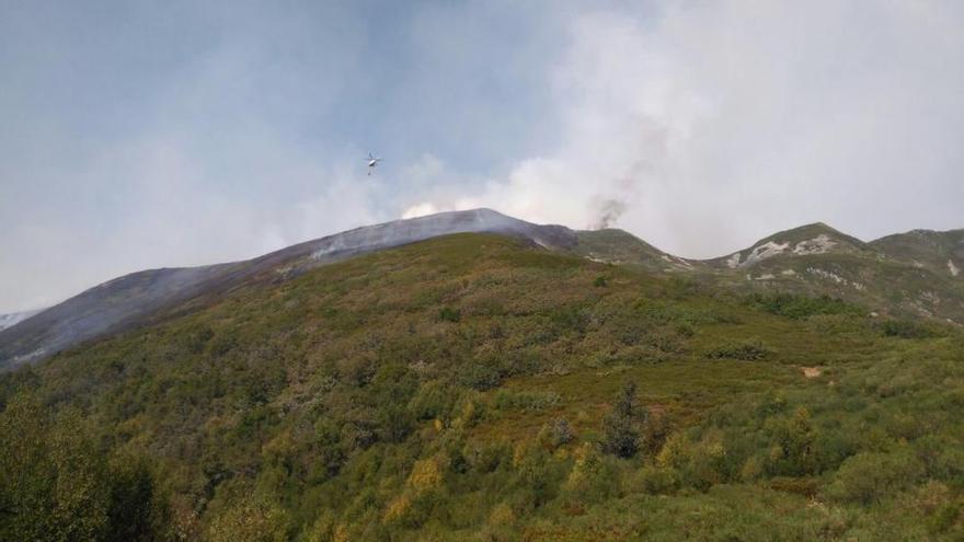 Un helicóptero de Medio Ambiente descarga agua en el incendio.