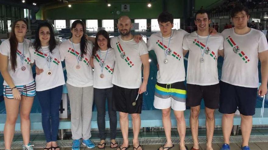 Los medallisas del CNS A Estrada posan con sus trofeos al borde de la piscina ourensana.